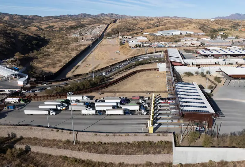 Cruce fronterizo con fila de camiones.
