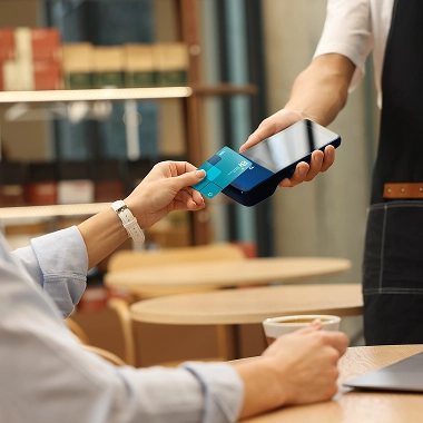 Mujer pagando en un restaurante con su Tarjeta Bi en un POS Bi