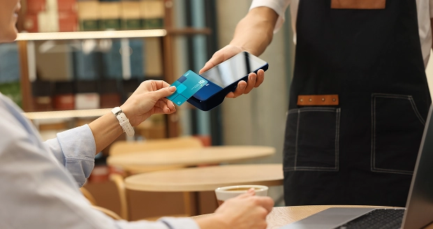 Mujer pagando en un restaurante con su Tarjeta Bi en un POS Bi